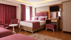 A hotel room with a bed, a desk, a chair, a TV, and a wardrobe.