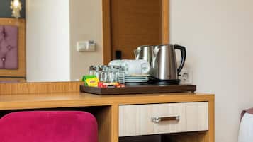 Une chambre d’hôtel avec un bureau en bois, une chaise rouge, une machine à café et divers ustensiles de cuisine.