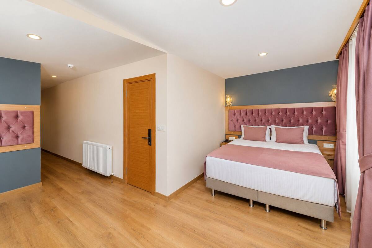 Un dormitorio con cama, una puerta de madera, un radiador y una mesita de noche.