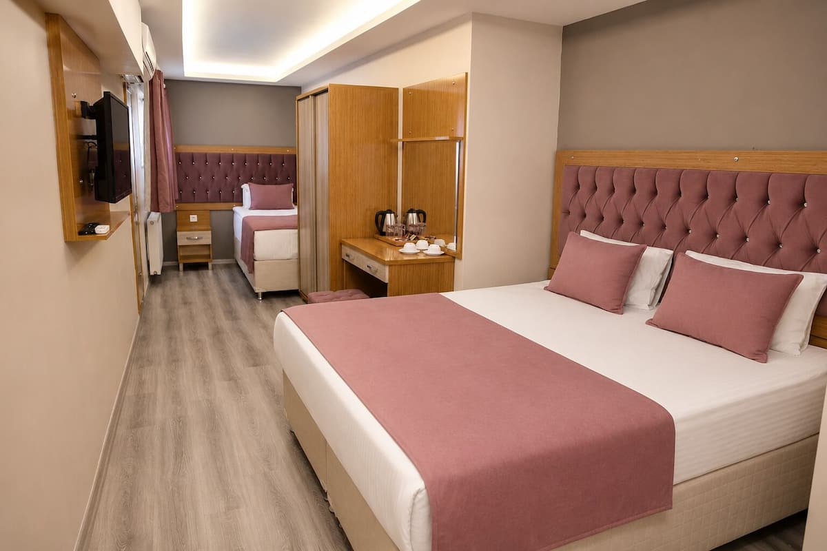 Habitación de hotel con una cama grande, un escritorio con silla, un armario y un televisor.