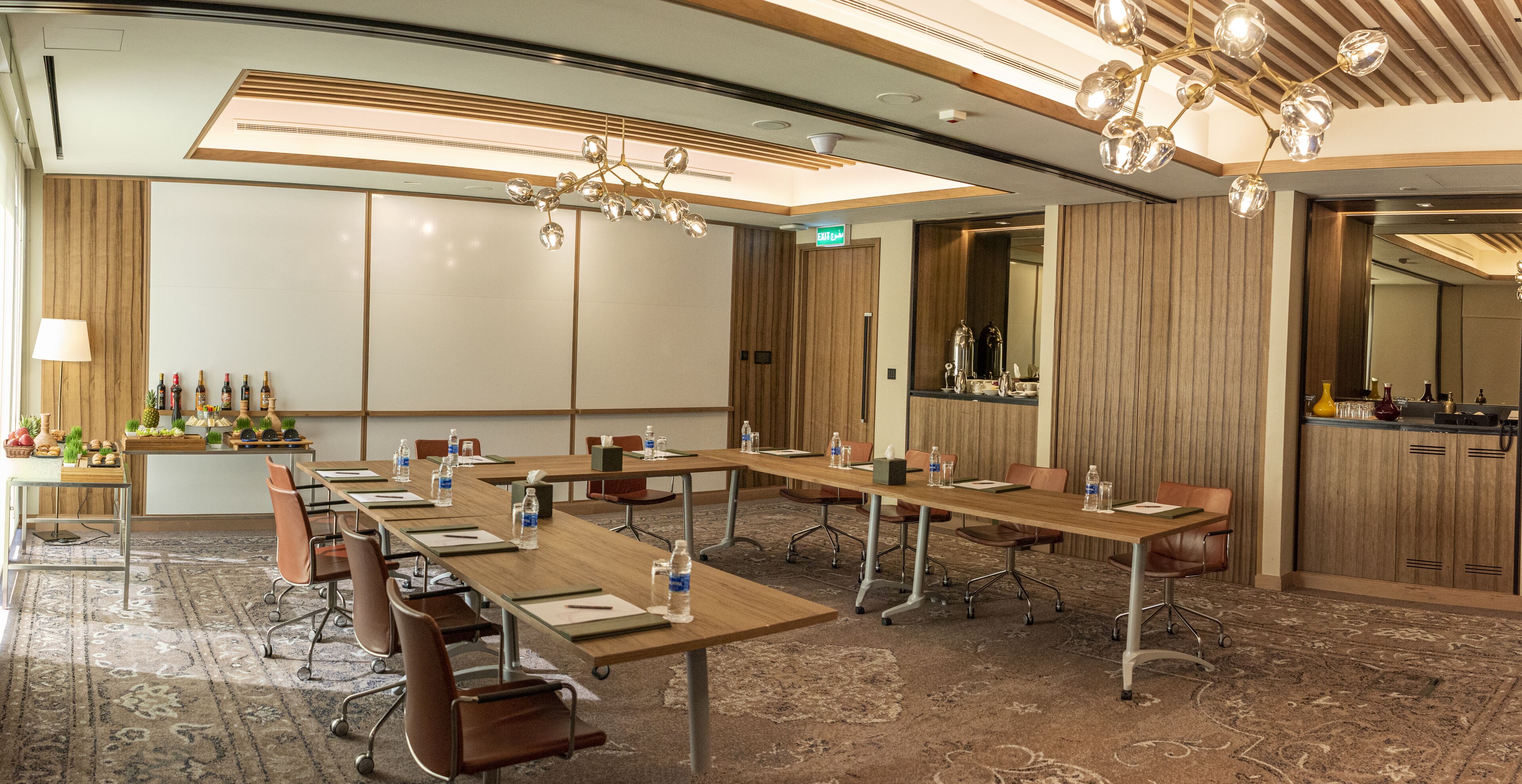A conference room with long tables, chairs, and a carpeted floor.