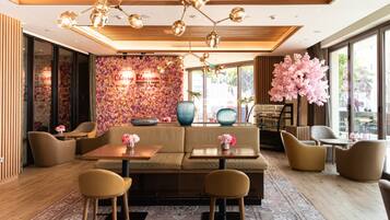 Ein modernes Interieur mit einer Couch, Stühlen, einem Tisch und einer Wand mit floraler Dekoration.