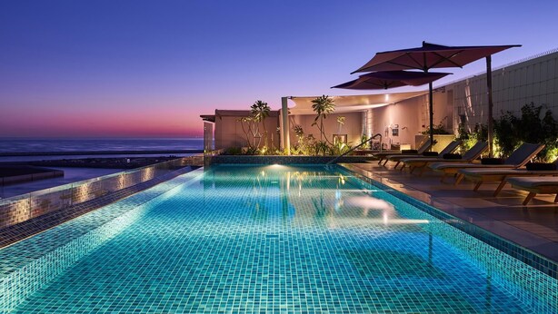 A swimming pool with a view of the ocean at dusk. - Mysk Al Mouj Hotel (Muscat)