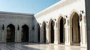 A courtyard with a series of arches and columns, featuring intricate tile work and traditional lanterns.