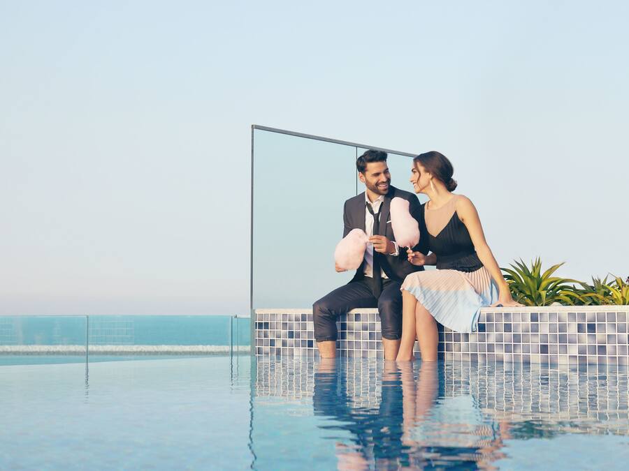 A couple sitting by a pool with a view of the ocean.