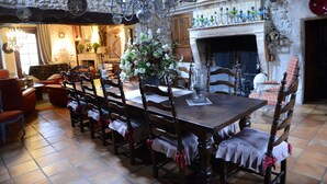 A dining room with a large wooden table, multiple chairs, a chandelier, and a fireplace.