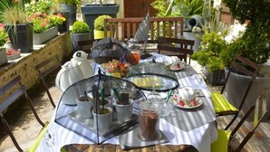 A round table with a glass top, surrounded by chairs, and various food items and containers on it.