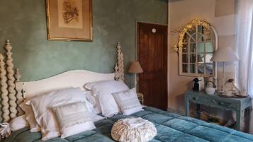 A bed with a quilted green cover, white pillows, and a decorative headboard.