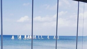 Blick auf das Meer mit Segelbooten von einem Fenster mit Blick auf einen Strand.