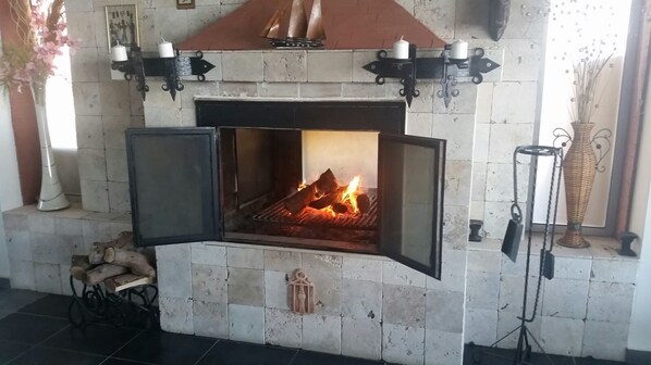 Una chimenea con fuego, paredes de azulejos y apliques decorativos.