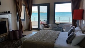 Ein Hotelzimmer mit einem Bett, einem Kamin, einem Balkon mit Meerblick und einer roten Lampe.