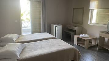 Habitación de hotel con dos camas, un escritorio pequeño, un espejo y una ventana con persianas.