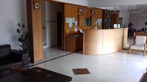 A reception area with a wooden reception desk, a clock, and framed certificates on the wall. - Hotel Paradise (Oropos)