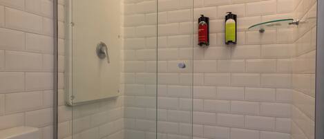 Una ducha con puerta de vidrio, un inodoro blanco y un piso con estampado de cuadros.