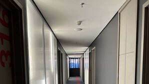 Ein langer, schmaler Gang mit einem roten Streifen auf dem Boden, der zu einem hellen Raum am Ende führt.
