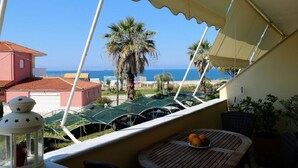 Un balcón con vista al mar, una mesa con fruta y un farol.