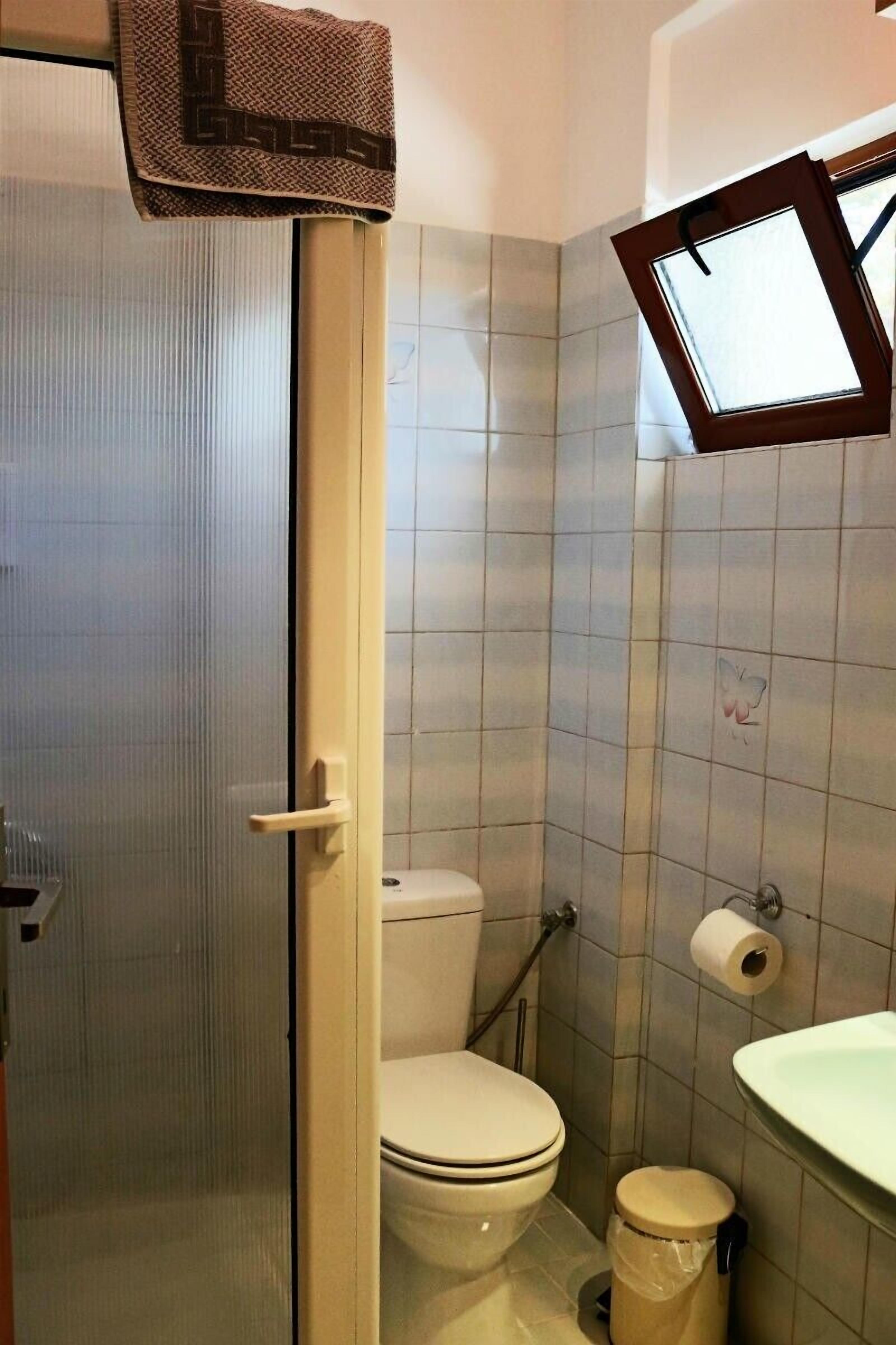 A bathroom with a toilet, a sink, and a shower area.