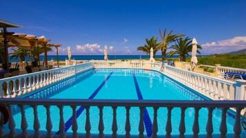 Alberca al aire libre, sombrillas en la alberca y camastros