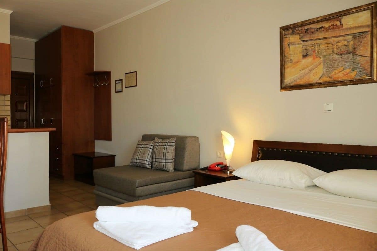 Habitación de hotel con cama, sofá, escritorio y un cuadro en la pared.