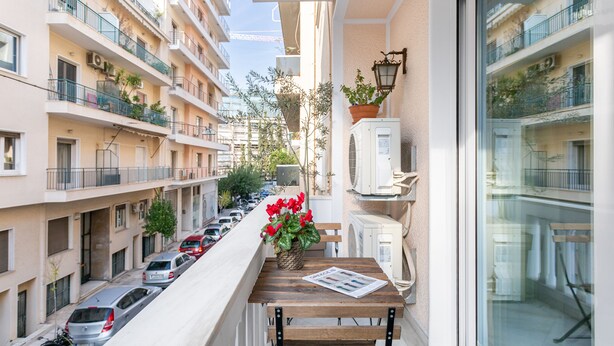A narrow balcony with a wooden table, a potted plant, and a newspaper. - Athens Squared Lofts (Athens)