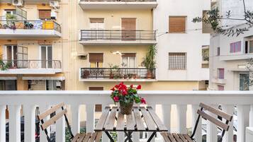 A balcony with a wooden table and benches, surrounded by a white railing.