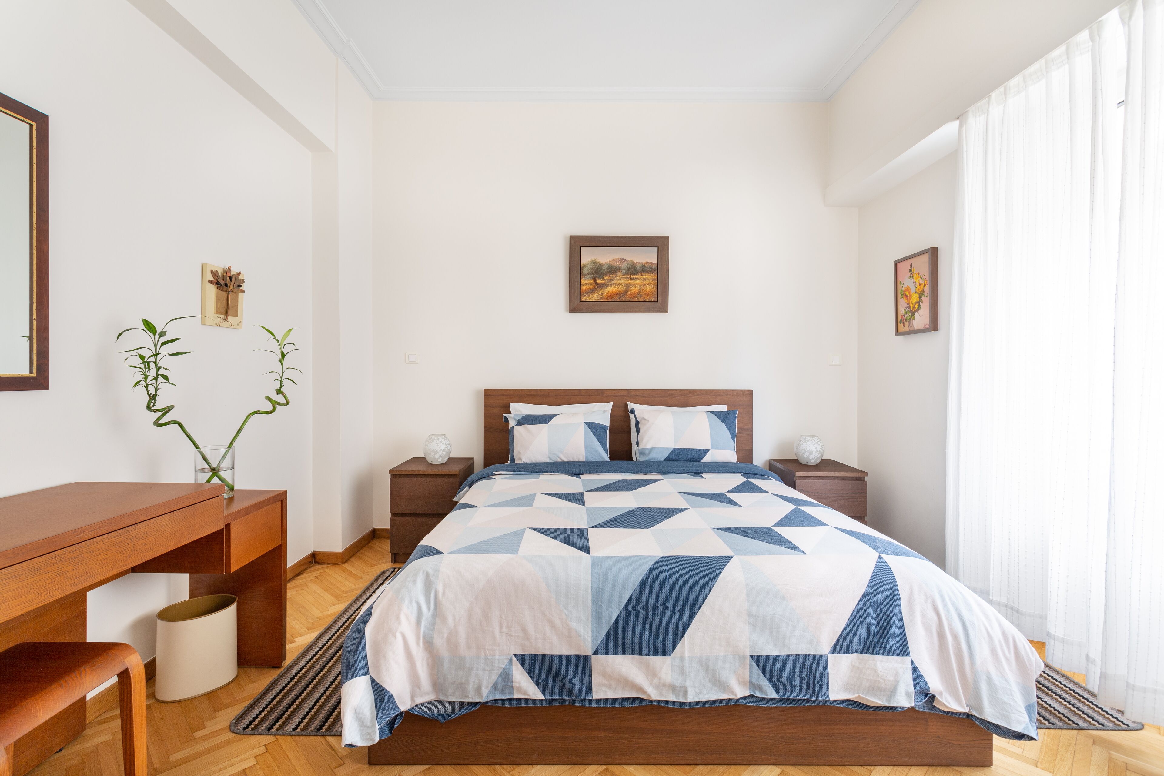 Un dormitorio con cama, mesitas de noche, escritorio y silla.