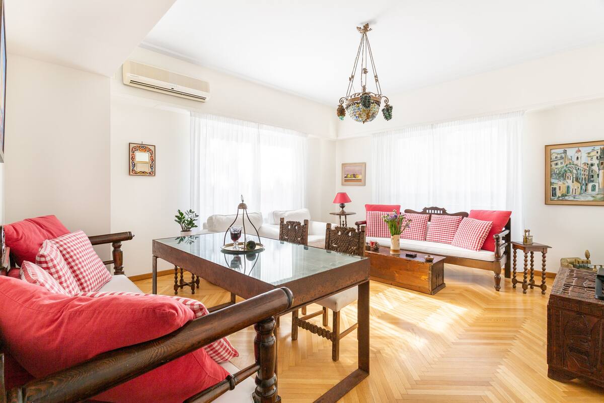 A spacious living room with a glass-top dining table, a sofa set, and a wooden coffee table.