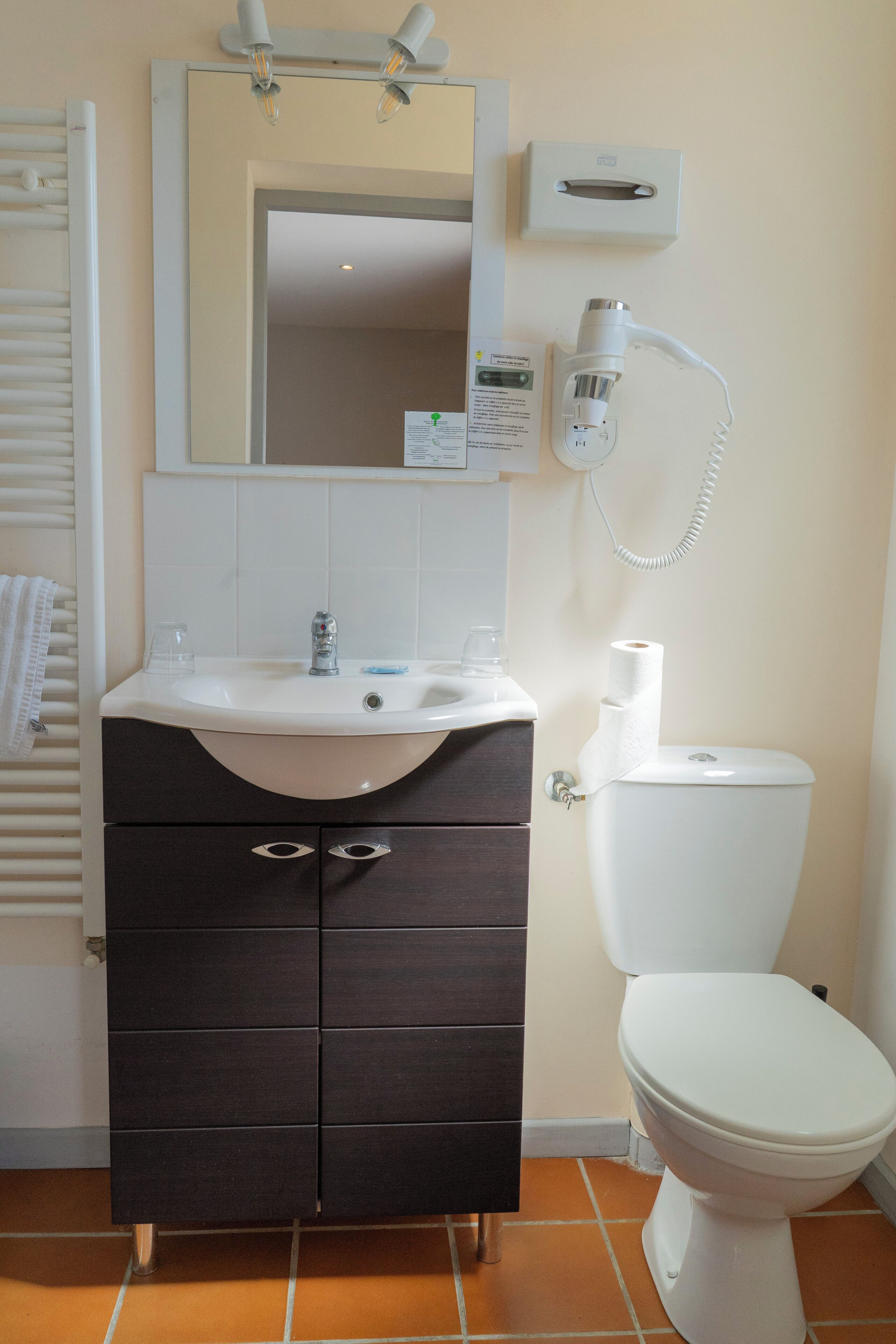 A bathroom with a white sink, dark wooden cabinet, white toilet, and a mirror above the sink.