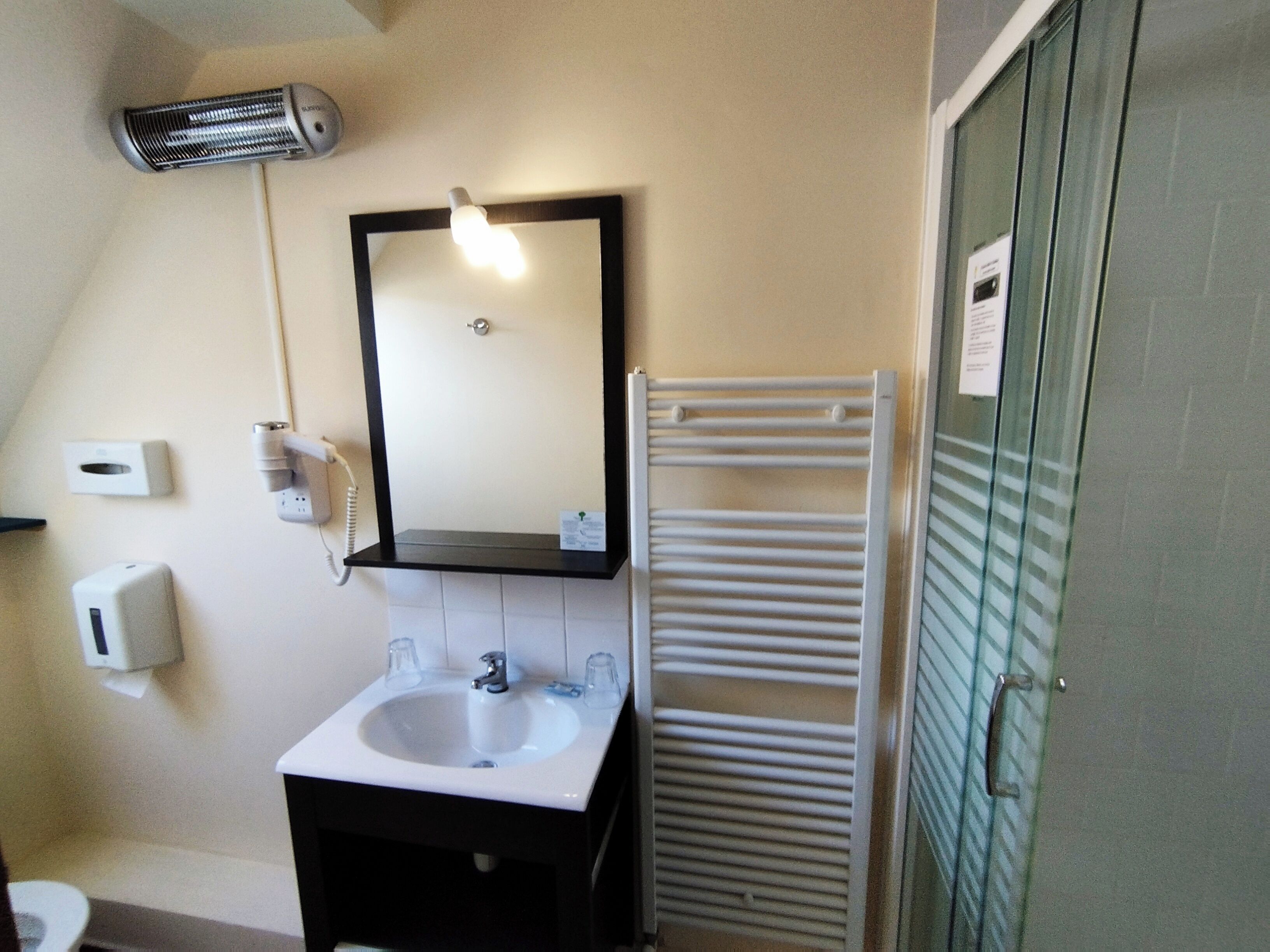 A bathroom with a sink, mirror, towel rack, and a hand dryer.