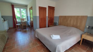 Une chambre à coucher avec un grand lit, une tête de lit en bois, une table de chevet avec une lampe et une chaise près d’une fenêtre.