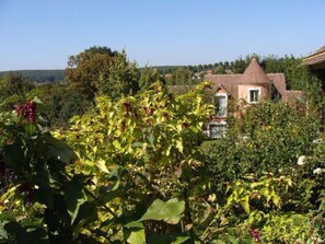 A house surrounded by greenery with a visible garden area. - Le Haut-Val résidence (Belleme)
