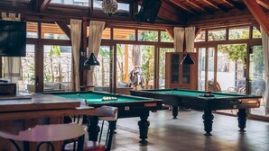A pool table in a room with large windows, wooden beams, and a television. - Mountain Valley Oludeniz (Fethiye)