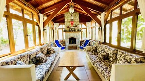 A spacious room with wooden beams, large windows, and a fireplace. - Mountain Valley Oludeniz (Fethiye)