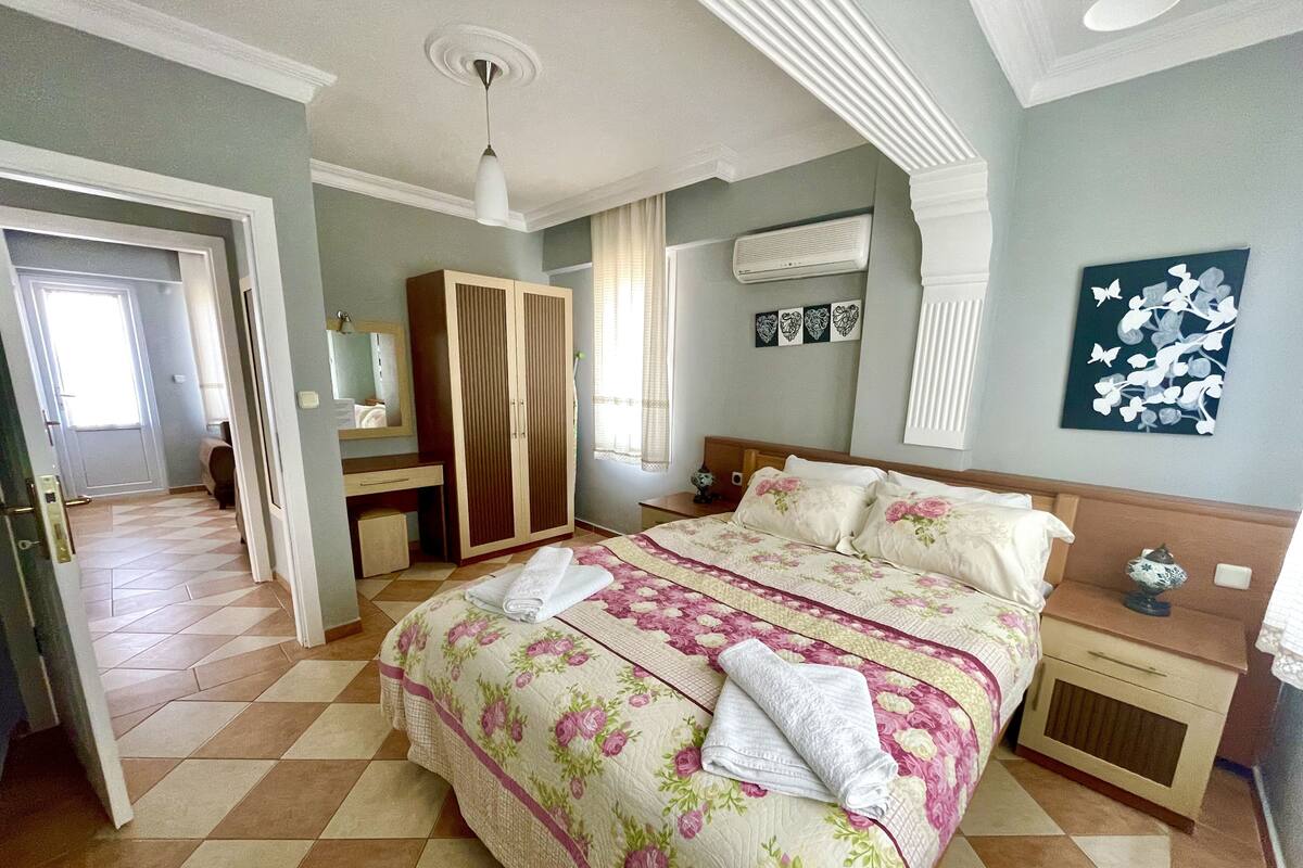 A bedroom with a bed, a wardrobe, a desk, and a mirror.
