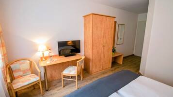 A room with a bed, a desk with a computer, a chair, a wardrobe, and a lamp.