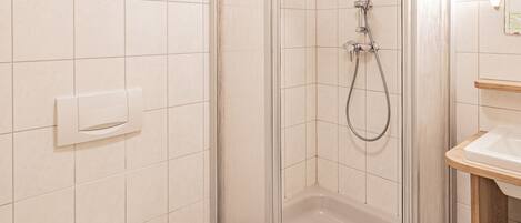 A bathroom with a glass-enclosed shower, a toilet, and a sink.