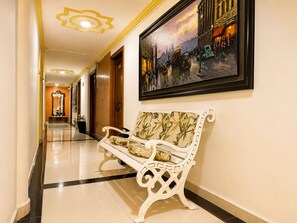 A hotel corridor with a bench, a framed painting, and a mirror. - Hotel Boutique Laureles Home (Medellín)