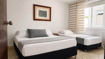 Habitación de hotel con dos camas, una obra de arte enmarcada en la pared y una ventana con persianas.
