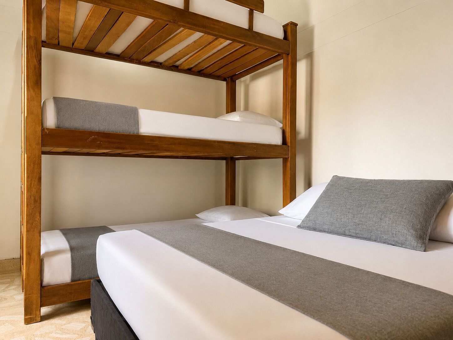 A bunk bed with a wooden frame, white bedding, and a grey pillow.