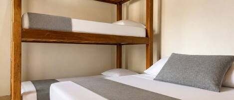 A bunk bed with a wooden frame, white bedding, and a grey pillow.