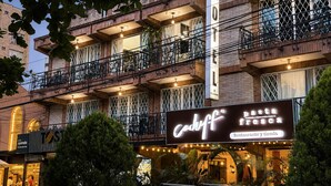 A multi-story building with balconies, a sign for 'Cody's Pasta Restaurante y Tienda,' and a visible hotel sign. - Hotel Boutique Laureles Home (Medellín)