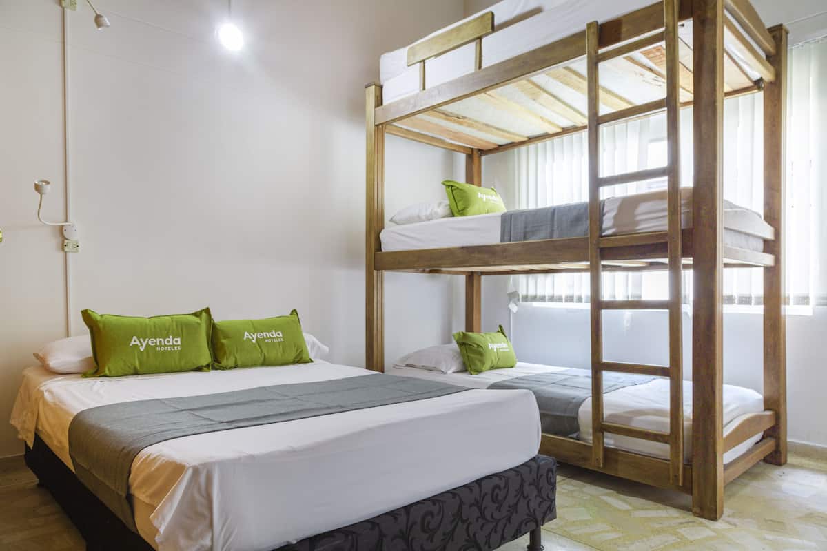 A bunk bed room with a lower bunk and a single bed, both with white bedding and green pillows.