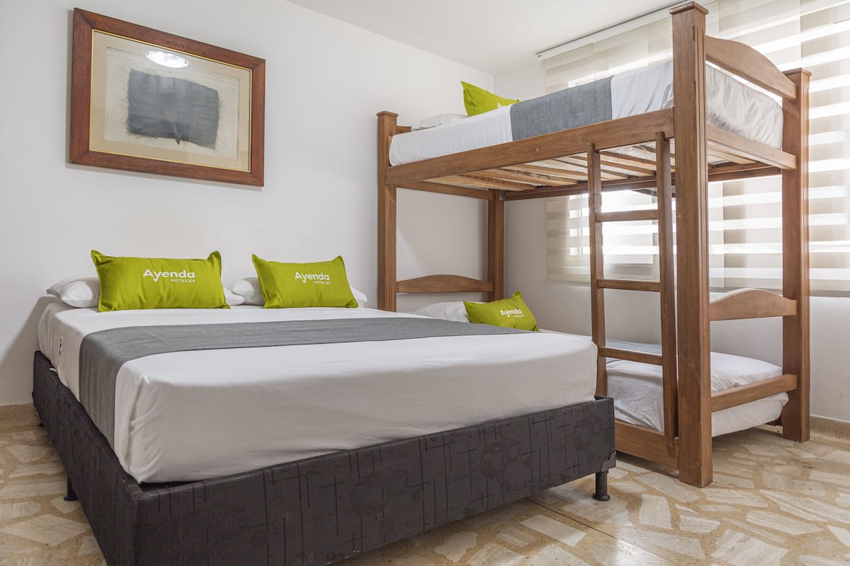 A bunk bed with a lower bed and a higher bunk, both with white bedding and green pillows.