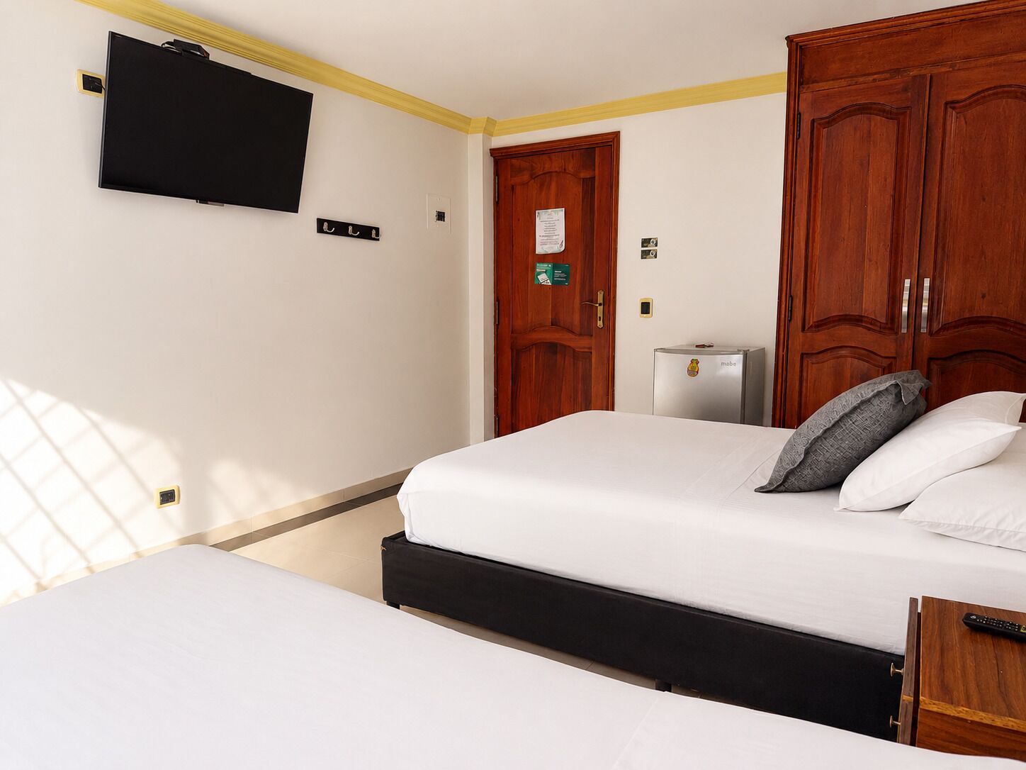 Une chambre d’hôtel équipée d’un lit, d’un téléviseur fixé au mur et d’un mini-bar.