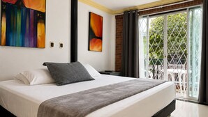 A hotel room with a large bed, a balcony with a view, and two abstract paintings on the wall. - Hotel Boutique Laureles Home (Medellín)