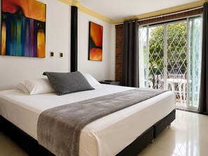 A hotel room with a large bed, a balcony with a view, and two abstract paintings on the wall. - Hotel Boutique Laureles Home (Medellín)