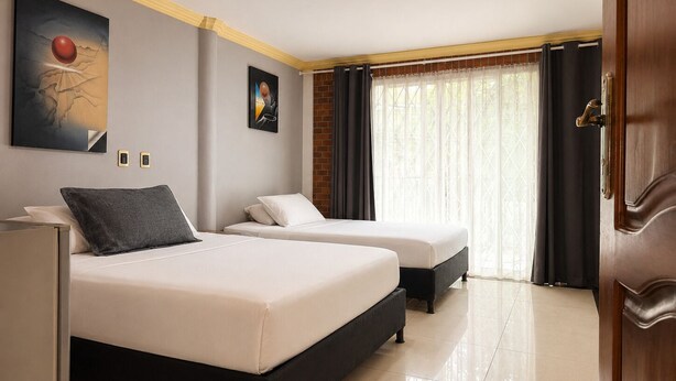 A hotel room with two beds, a large window with curtains, and a modern ceiling design. - Hotel Boutique Laureles Home (Medellín)