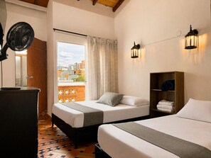 Ett hotellrum med en säng, ett nattduksbord, en lampa och utsikt över staden.