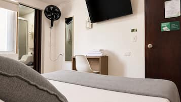 Une chambre d’hôtel équipée d’un lit, d’un téléviseur à écran plat, d’un miroir, d’un porte-serviettes et d’une porte.