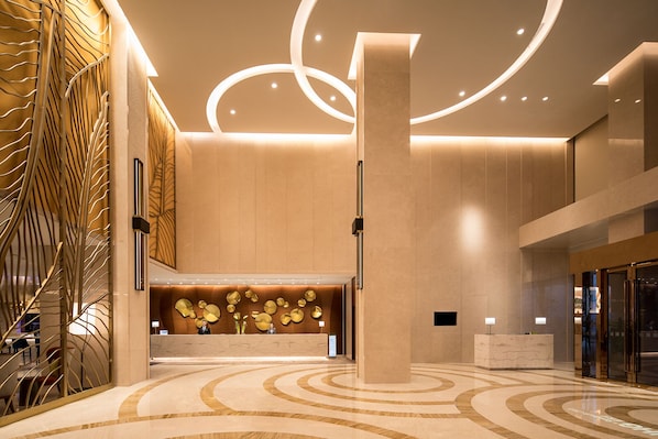 A modern lobby with a marble floor, a reception desk, and a decorative wall with circular patterns. - Holiday Inn Suzhou Taihu Lake by IHG (Suzhou)